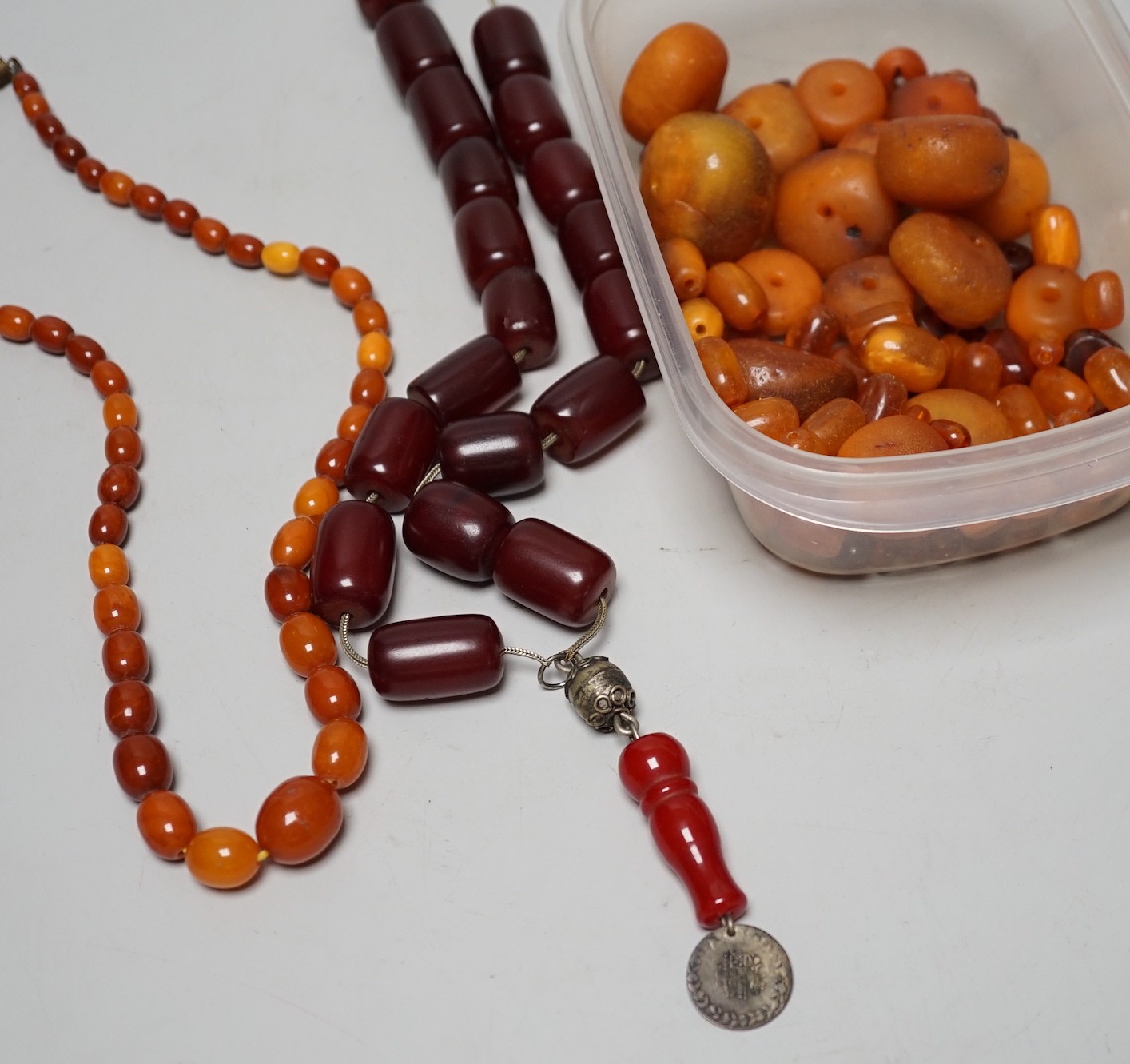 A single strand graduated amber bead necklace, 54cm gross weight 30 grams, together with loose amber beads, gross 153 grams and a simulated cherry amber necklace.